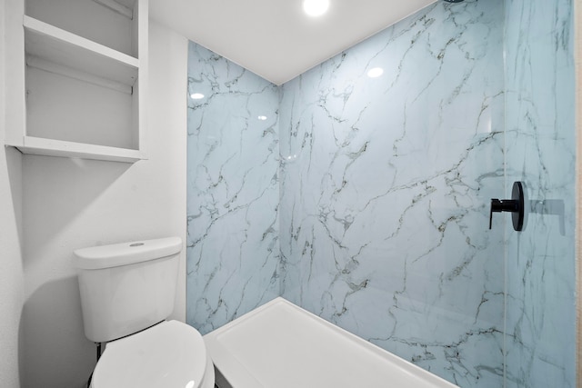 full bathroom featuring toilet and a marble finish shower
