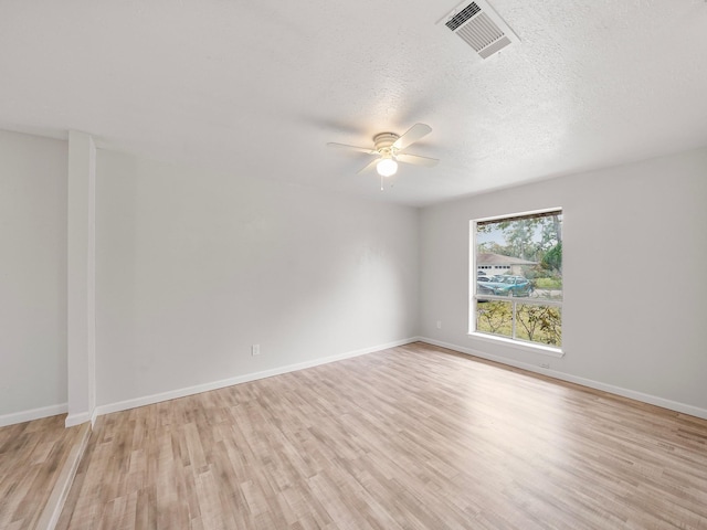 empty room with a ceiling fan, light wood-style floors, a textured ceiling, and baseboards