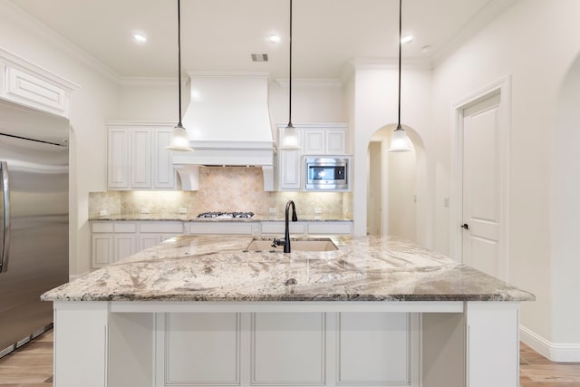 kitchen featuring built in appliances, a sink, ornamental molding, tasteful backsplash, and light wood-style floors