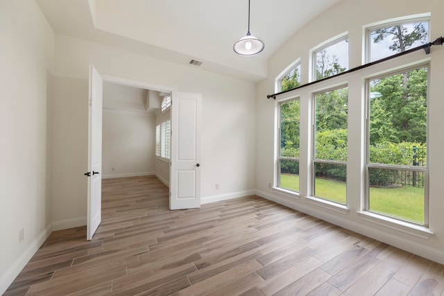 unfurnished bedroom featuring light wood finished floors, baseboards, and lofted ceiling