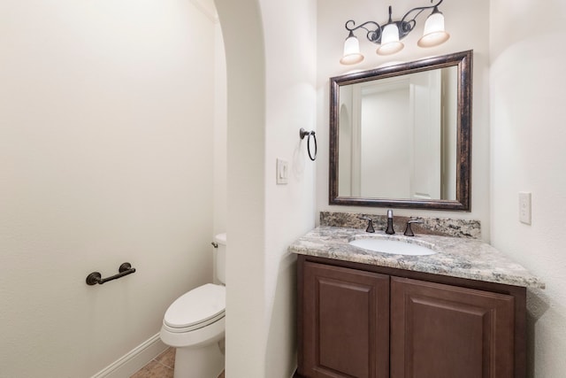 half bathroom with toilet, vanity, tile patterned floors, and baseboards