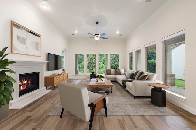 living area featuring ornamental molding, ceiling fan, a glass covered fireplace, recessed lighting, and wood finished floors