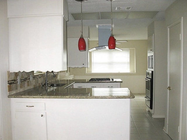 kitchen featuring a sink, ventilation hood, a peninsula, white cabinets, and tile patterned floors