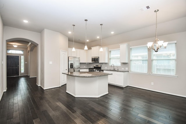 7718 Collina Landing Trl, Richmond, TX 77407 - kitchen with stainless steel appliances, arched walkways, a kitchen island, baseboards, and recessed lighting