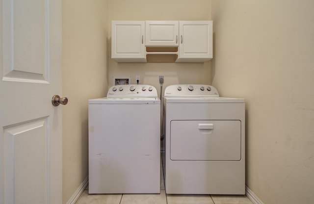 laundry area with washer and clothes dryer, cabinet space, light tile patterned floors, and baseboards
