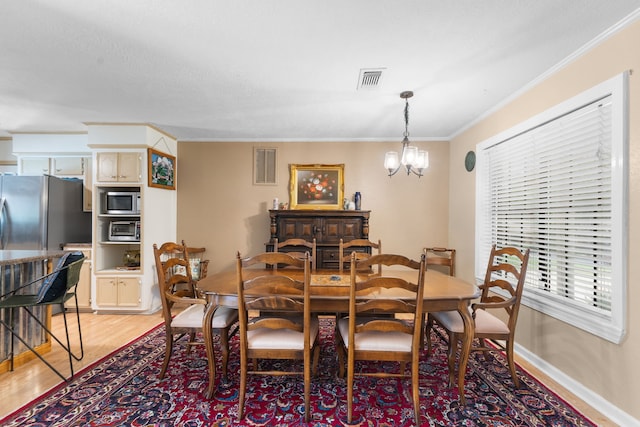 dining area featuring light wood-style flooring, crown molding, a chandelier, and baseboards