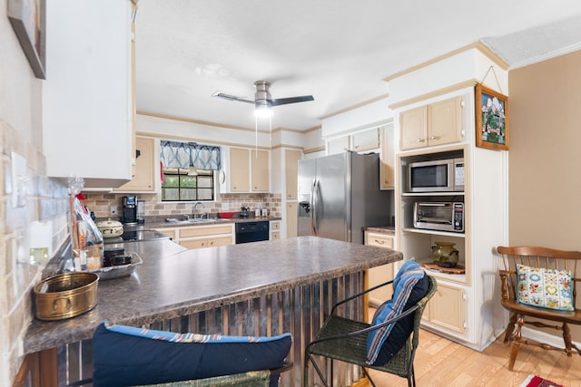 kitchen featuring appliances with stainless steel finishes, light wood-style floors, backsplash, a peninsula, and a sink