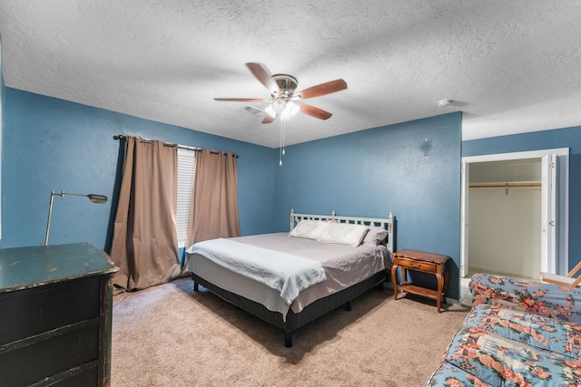 bedroom featuring a textured ceiling, light colored carpet, a ceiling fan, and a closet