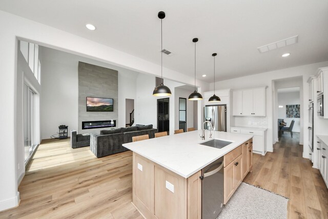 4914 Olive Province Ln, Manvel, TX 77578 - kitchen featuring a sink, appliances with stainless steel finishes, light wood finished floors, light countertops, and a fireplace