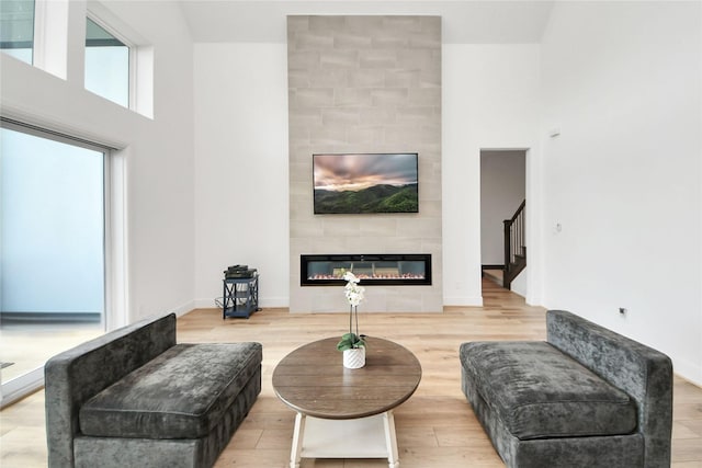 4914 Olive Province Ln, Manvel, TX 77578 - living room with a tile fireplace, light wood-type flooring, a high ceiling, baseboards, and stairway