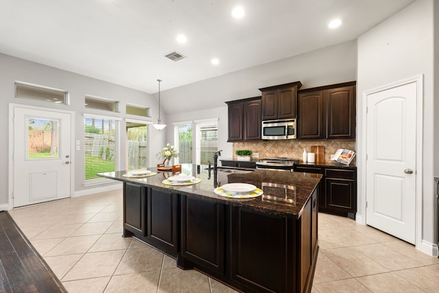 2314 Laurel Loch Ln, Pearland, TX 77584 - kitchen with stainless steel appliances, a sink, decorative backsplash, dark stone counters, and a kitchen island with sink