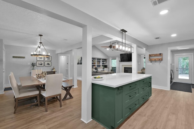 914 Rustic Oaks Dr, Magnolia, TX 77354 - kitchen with green cabinetry, a fireplace, light wood finished floors, baseboards, and lofted ceiling