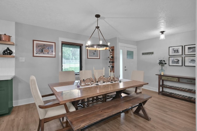 914 Rustic Oaks Dr, Magnolia, TX 77354 - dining room featuring a chandelier, light wood-type flooring, a textured ceiling, and baseboards