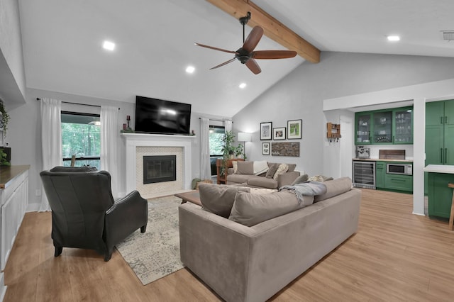 914 Rustic Oaks Dr, Magnolia, TX 77354 - living area featuring beverage cooler, a glass covered fireplace, beamed ceiling, light wood-style flooring, and a dry bar