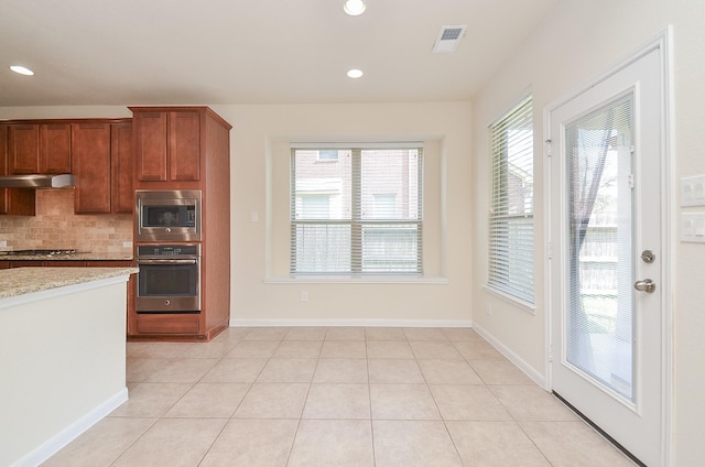 kitchen featuring stainless steel appliances, under cabinet range hood, tasteful backsplash, light stone counters, and recessed lighting