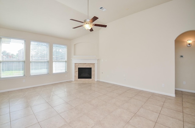 unfurnished living room with ceiling fan, arched walkways, light tile patterned floors, plenty of natural light, and high vaulted ceiling