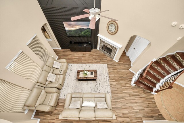 living area with wood finished floors, a ceiling fan, a fireplace, and baseboards