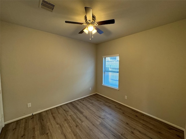 unfurnished room featuring dark wood-type flooring, ceiling fan, and baseboards