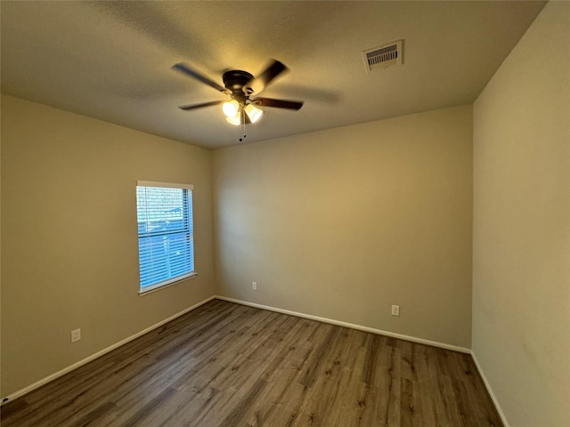 unfurnished room featuring dark wood-type flooring, ceiling fan, baseboards, and a textured ceiling