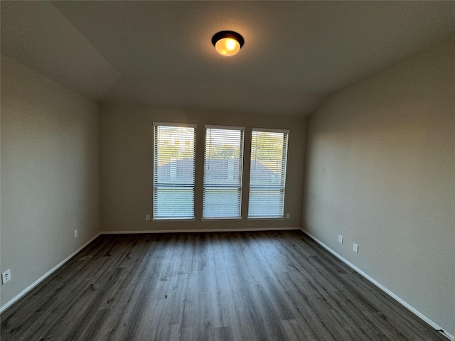 unfurnished room with dark wood finished floors, baseboards, and lofted ceiling