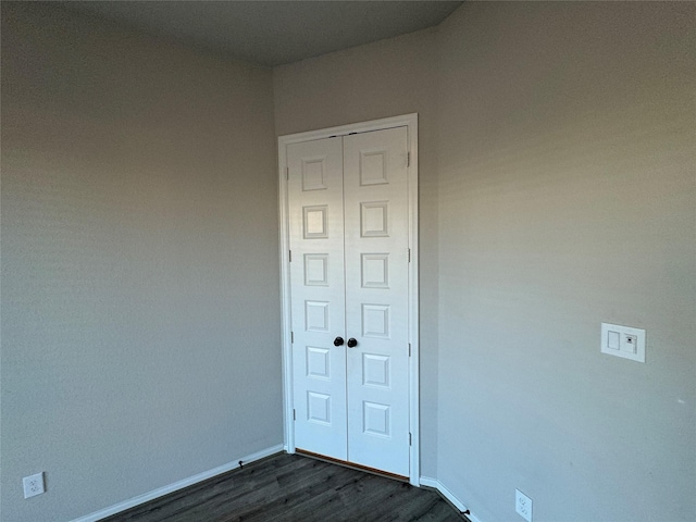empty room featuring baseboards and dark wood-style flooring