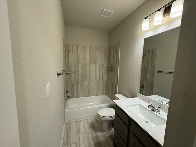 bathroom featuring a textured wall, toilet, vanity, and tub / shower combination
