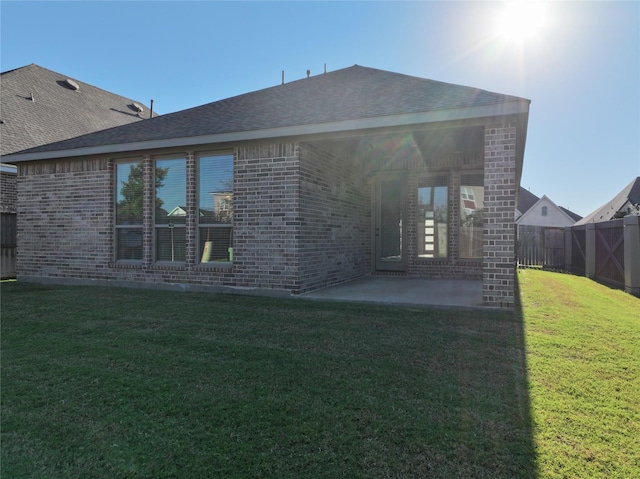 back of property with brick siding, a patio area, and roof with shingles