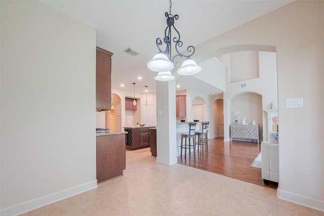 dining room featuring arched walkways, a chandelier, baseboards, light tile patterned floors, and recessed lighting