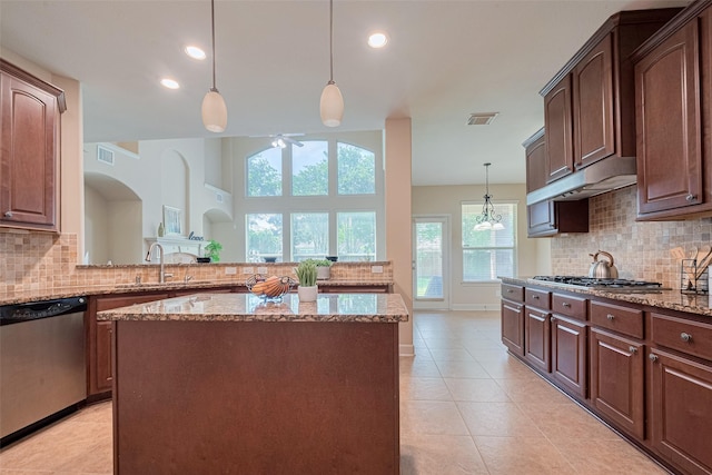 kitchen featuring appliances with stainless steel finishes, a sink, ceiling fan, light stone countertops, and decorative backsplash