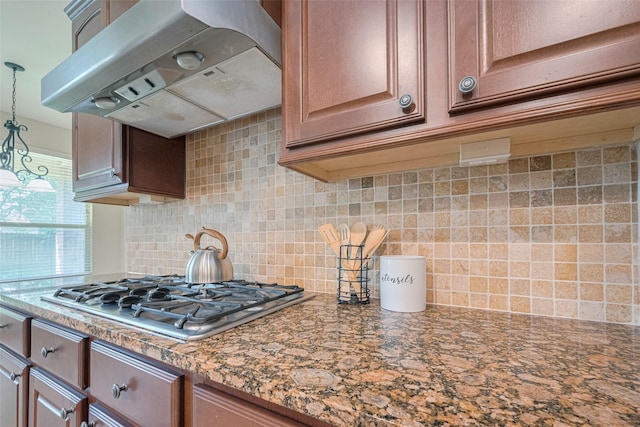 kitchen with under cabinet range hood, stainless steel gas cooktop, decorative backsplash, and decorative light fixtures
