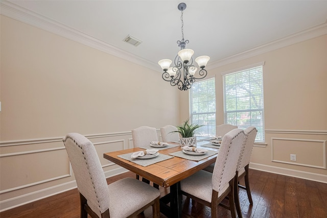 dining area with crown molding, a chandelier, wainscoting, dark wood finished floors, and a decorative wall