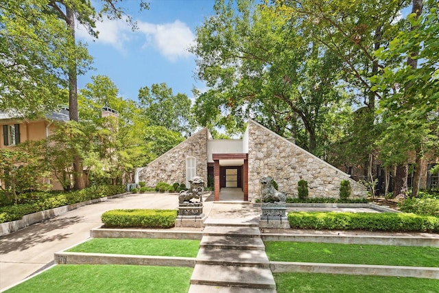 mid-century home featuring stone siding, stucco siding, and driveway