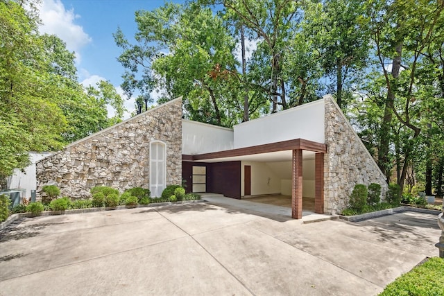 view of side of property featuring stone siding, stucco siding, and a garage