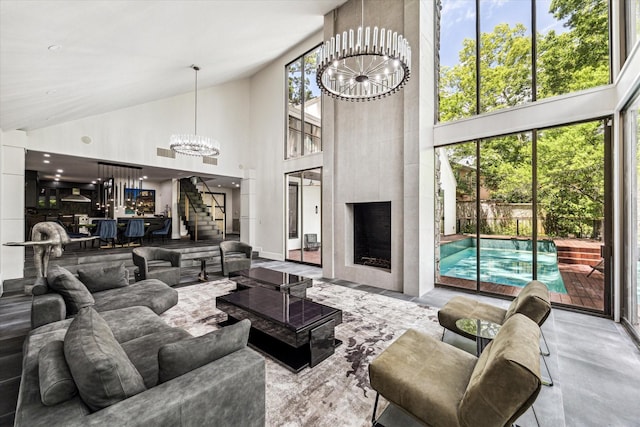 living room featuring a chandelier, high vaulted ceiling, stairway, and a large fireplace