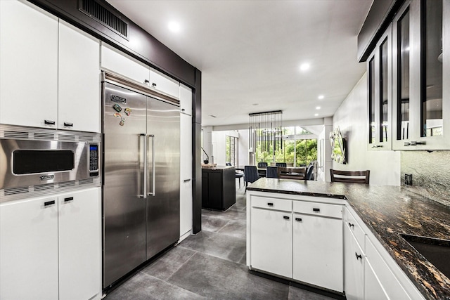 kitchen featuring built in appliances, white cabinets, a peninsula, recessed lighting, and a sink