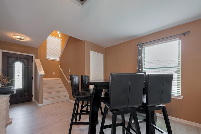 dining room featuring stairway, baseboards, healthy amount of natural light, and light wood-style flooring