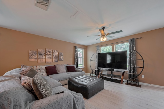 living room featuring a ceiling fan, baseboards, and light wood-style floors
