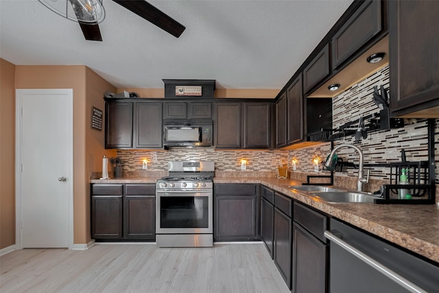 kitchen featuring stainless steel appliances, a sink, tasteful backsplash, light wood-style floors, and dark brown cabinets