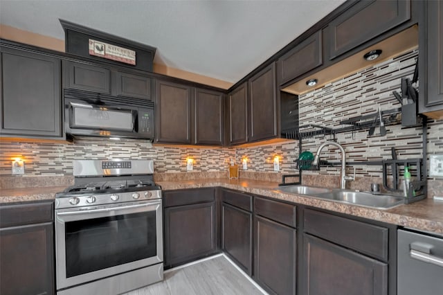 kitchen featuring appliances with stainless steel finishes, a sink, dark brown cabinets, decorative backsplash, and light countertops