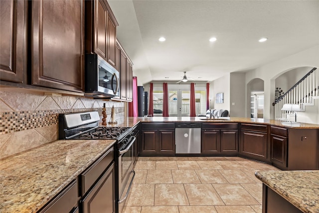 kitchen with stainless steel appliances, a ceiling fan, arched walkways, decorative backsplash, and recessed lighting