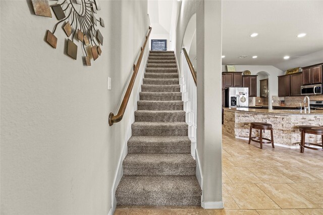 stairway with arched walkways, recessed lighting, tile patterned flooring, and baseboards