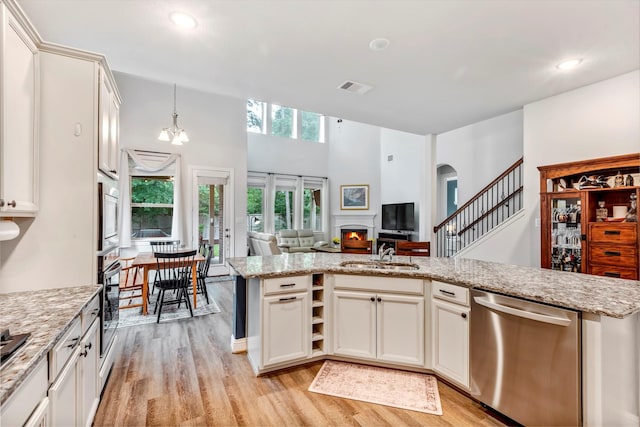 116 Brighton Woods Ct, Conroe, TX 77318 - kitchen featuring appliances with stainless steel finishes, a sink, a warm lit fireplace, light wood-style floors, and open floor plan