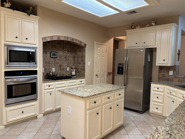 3923 Fordham Park Ct, Pasadena, TX 77058 - kitchen with appliances with stainless steel finishes, light tile patterned floors, backsplash, a skylight, and light stone countertops