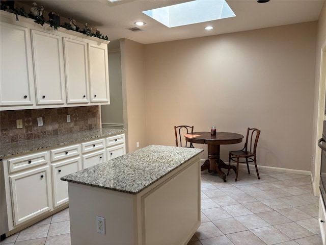 3923 Fordham Park Ct, Pasadena, TX 77058 - kitchen featuring a skylight, a center island, light tile patterned flooring, backsplash, and white cabinets