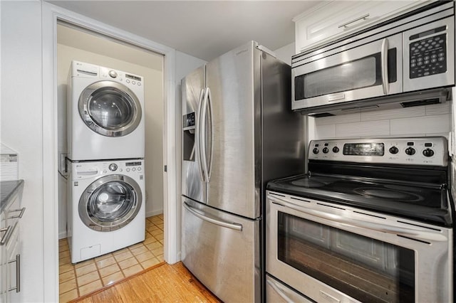 kitchen featuring stainless steel appliances, estacked washer and dryer, decorative backsplash, and light wood-style floors