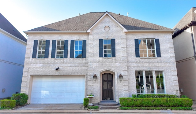 view of front of house featuring brick siding, a garage, roof with shingles, and driveway