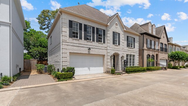 view of front facade featuring driveway, a garage, brick siding, fence, and roof with shingles