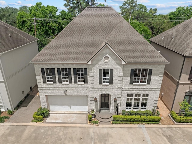view of front of house with an attached garage, driveway, a shingled roof, and brick siding