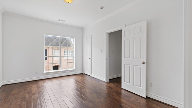 unfurnished room featuring crown molding, dark wood finished floors, and baseboards