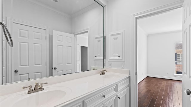 bathroom featuring ornamental molding, wood finished floors, double vanity, and baseboards